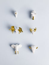 6 assorted white and gold animal head push pins on a light blue background